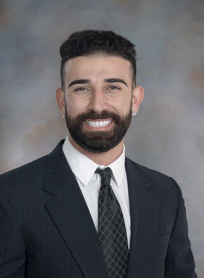 Professional headshot: smiling bearded man in suit